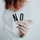 Setting boundaries to people Close-up of a person holding a "No" sign, symbolizing rejection or disagreement.